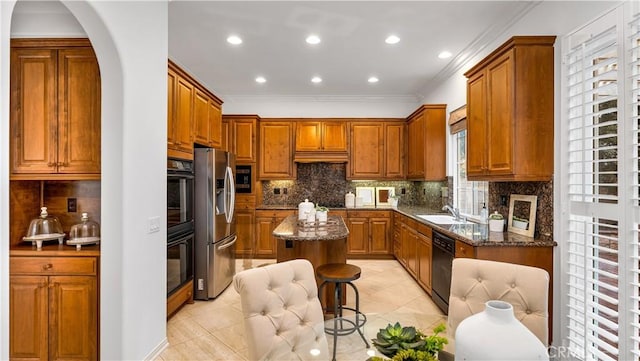 kitchen featuring stainless steel refrigerator with ice dispenser, sink, dishwasher, a kitchen island, and dark stone counters