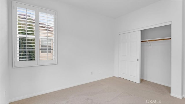 unfurnished bedroom featuring light carpet and a closet