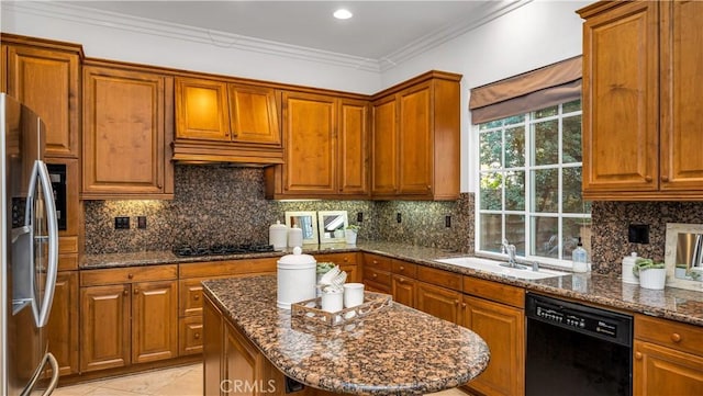 kitchen with sink, crown molding, black appliances, a kitchen island, and dark stone counters