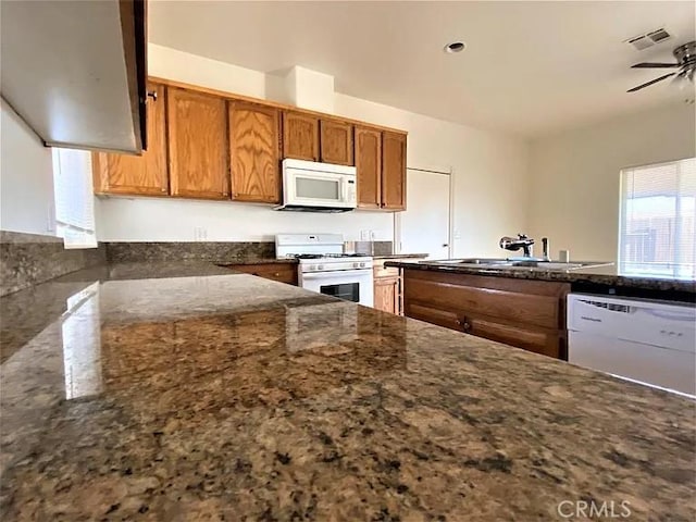 kitchen with ceiling fan, white appliances, sink, and dark stone countertops