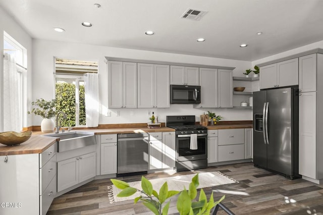 kitchen featuring gray cabinets, appliances with stainless steel finishes, butcher block countertops, sink, and dark hardwood / wood-style flooring