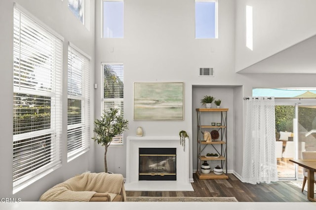 living room with plenty of natural light, a towering ceiling, and dark hardwood / wood-style flooring