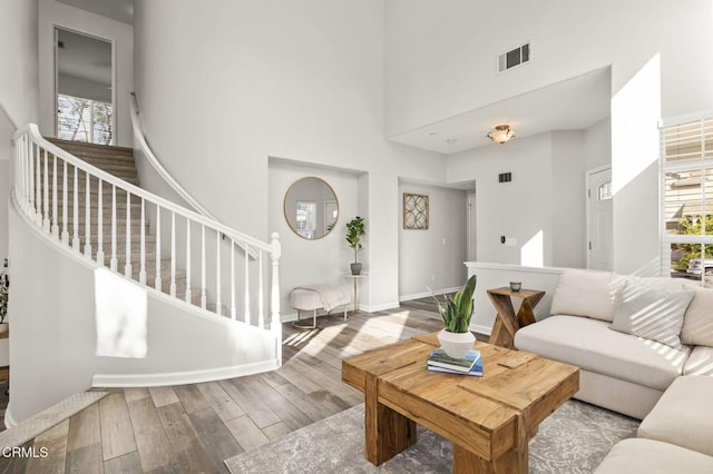 living room with a healthy amount of sunlight, light hardwood / wood-style flooring, and a high ceiling