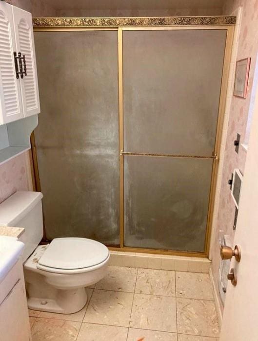 bathroom with a shower with door, vanity, and toilet