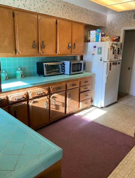 kitchen with white refrigerator and tile counters