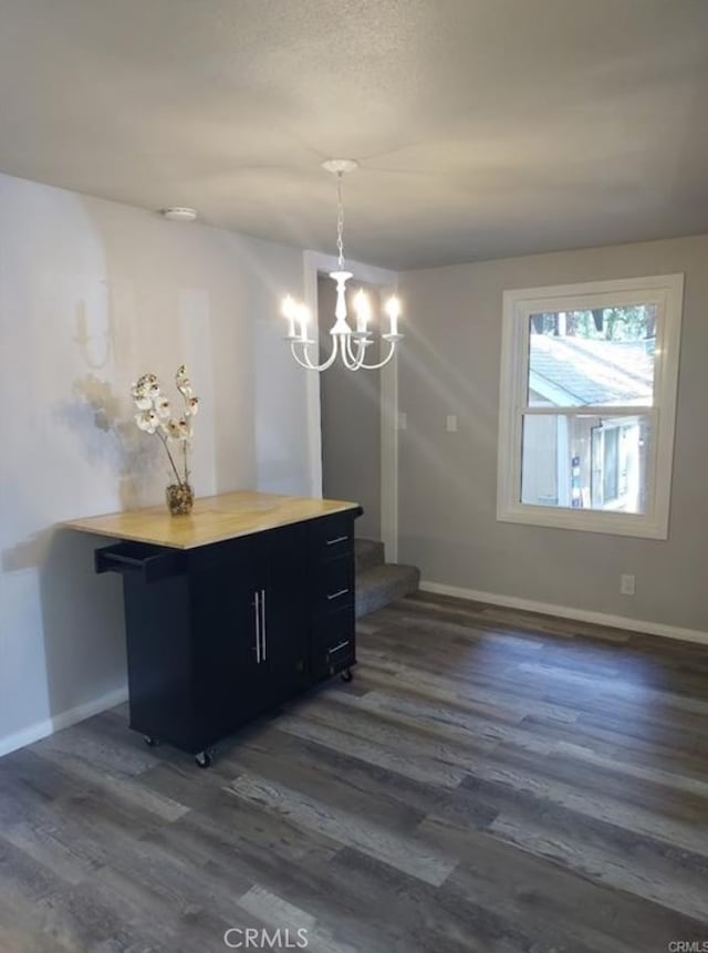 unfurnished dining area featuring dark hardwood / wood-style flooring, a chandelier, and a textured ceiling