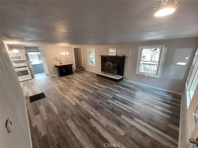 unfurnished living room with dark hardwood / wood-style floors, a brick fireplace, and a textured ceiling