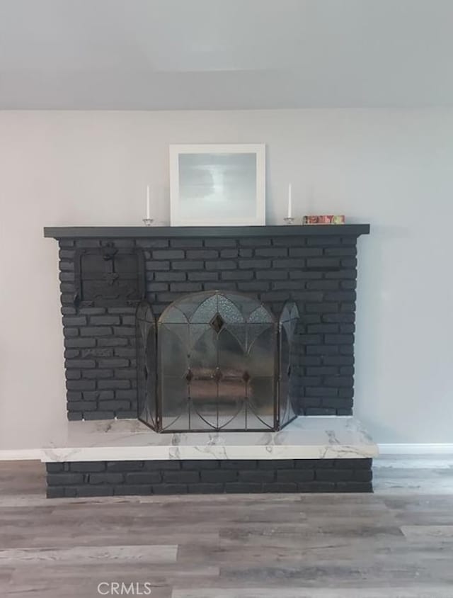 details with a brick fireplace and wood-type flooring