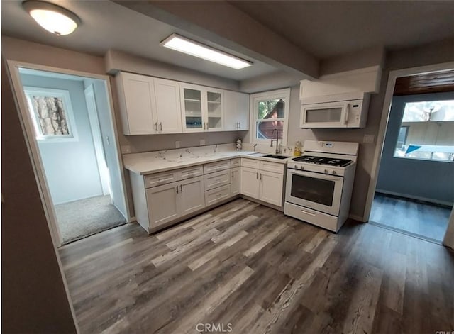 kitchen with white appliances, dark hardwood / wood-style flooring, sink, and white cabinets