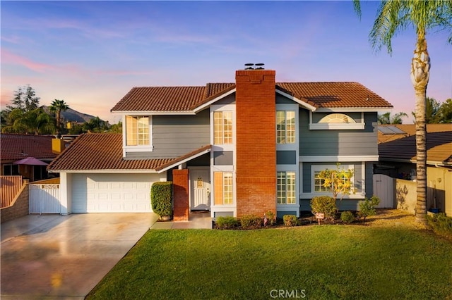 view of front of home featuring a tile roof, fence, concrete driveway, a lawn, and a chimney