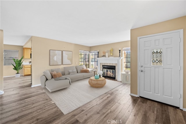 living room with baseboards, wood finished floors, and a tile fireplace