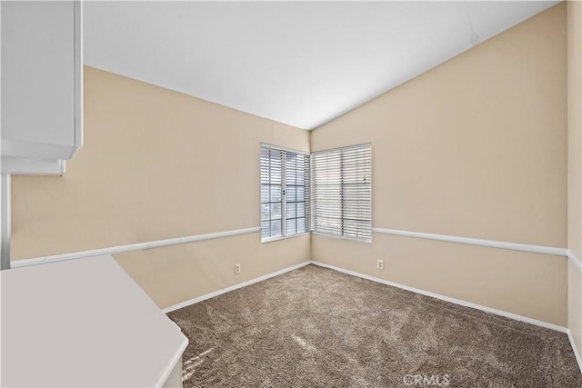 empty room featuring baseboards, vaulted ceiling, and carpet flooring