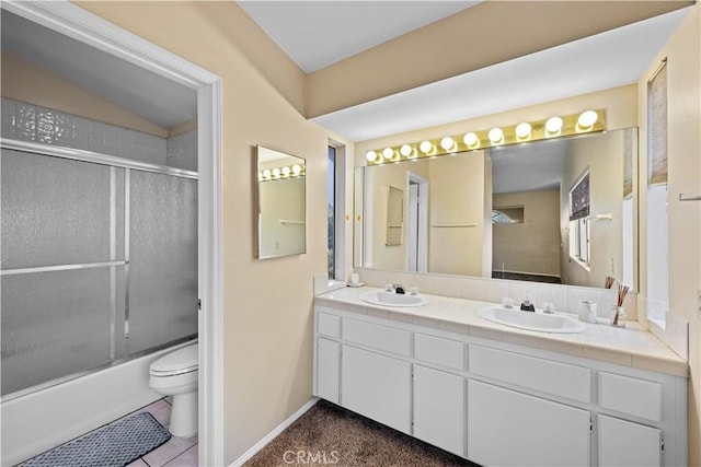 full bathroom with double vanity, shower / bath combination with glass door, toilet, and a sink