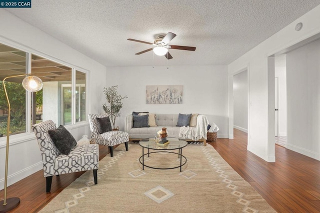 living room featuring hardwood / wood-style flooring, a textured ceiling, and ceiling fan