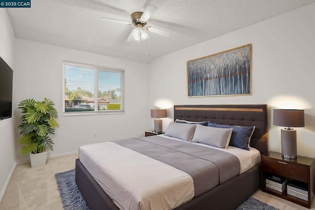 bedroom featuring ceiling fan, light carpet, and a textured ceiling