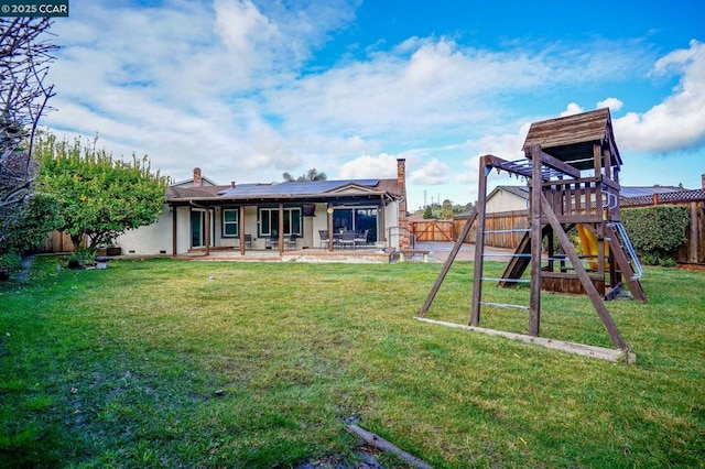 exterior space with a playground, a patio, a yard, and solar panels