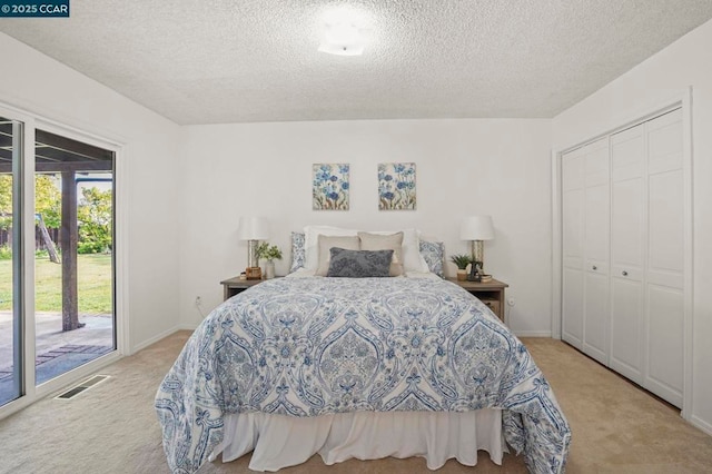 bedroom featuring light colored carpet, access to exterior, a closet, and a textured ceiling