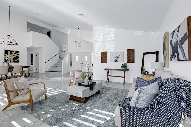 living room with an inviting chandelier, high vaulted ceiling, and french doors