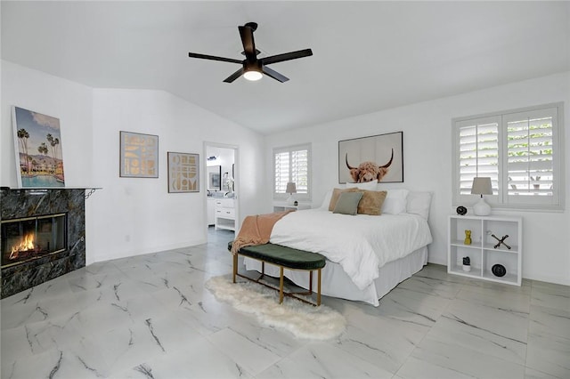 bedroom with ceiling fan, lofted ceiling, a high end fireplace, and ensuite bath