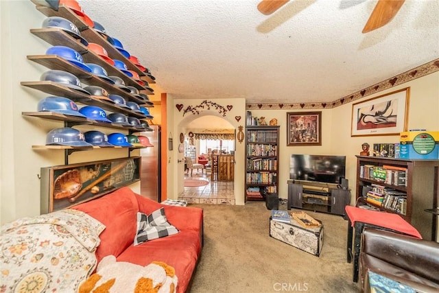 living room with ceiling fan, carpet floors, and a textured ceiling