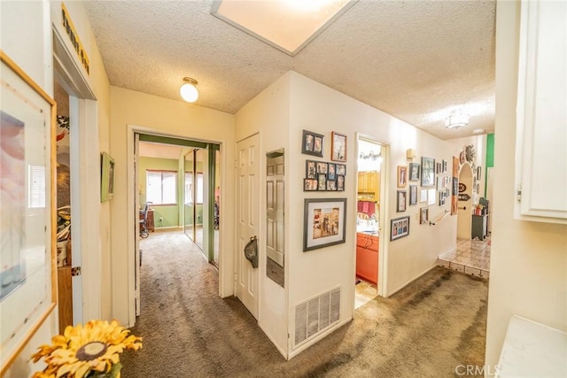 hallway featuring carpet flooring and a textured ceiling