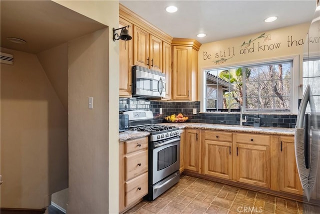 kitchen featuring appliances with stainless steel finishes, backsplash, a sink, and light stone counters