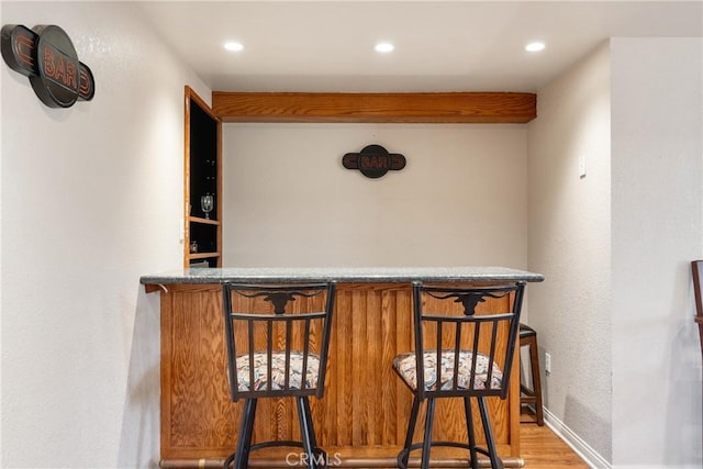 bar with baseboards, a bar, wood finished floors, and recessed lighting