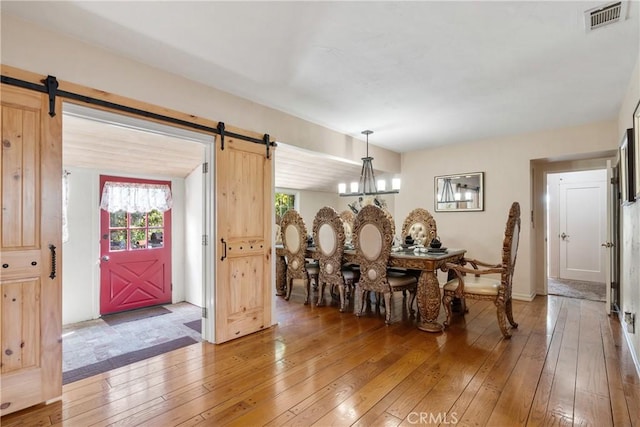 dining area featuring light wood-style floors, a barn door, and visible vents