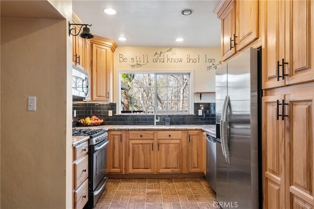 kitchen featuring appliances with stainless steel finishes, backsplash, a sink, and recessed lighting