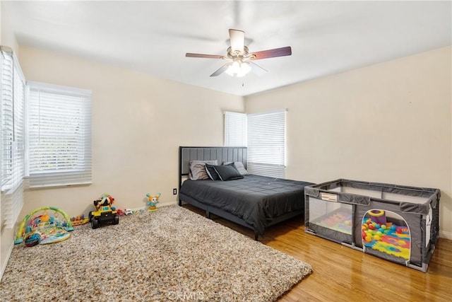 bedroom with a ceiling fan, baseboards, and wood finished floors