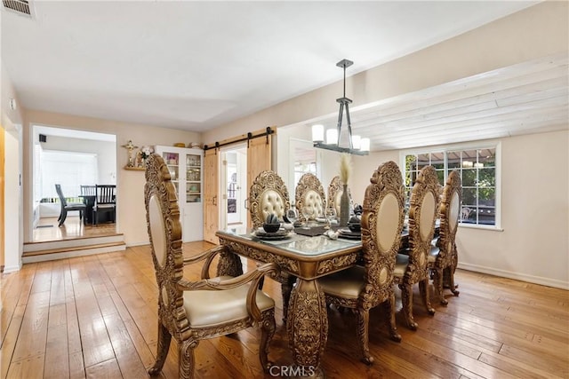 dining space featuring a barn door, plenty of natural light, visible vents, and light wood-style floors