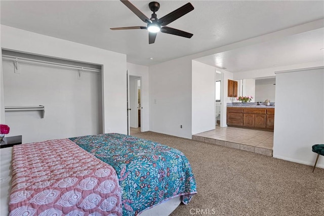 bedroom featuring sink, ensuite bath, light carpet, a closet, and ceiling fan
