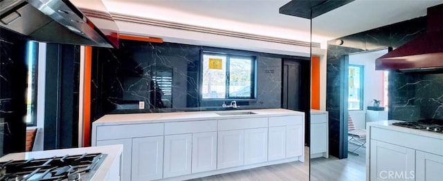 kitchen with light countertops, white cabinetry, a sink, and gas stovetop