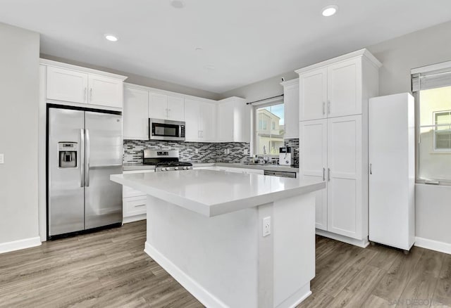 kitchen featuring a kitchen island, appliances with stainless steel finishes, white cabinets, and light hardwood / wood-style floors