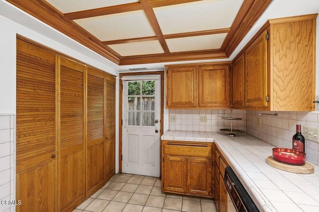 kitchen featuring dishwashing machine, decorative backsplash, ornamental molding, tile counters, and light tile patterned floors