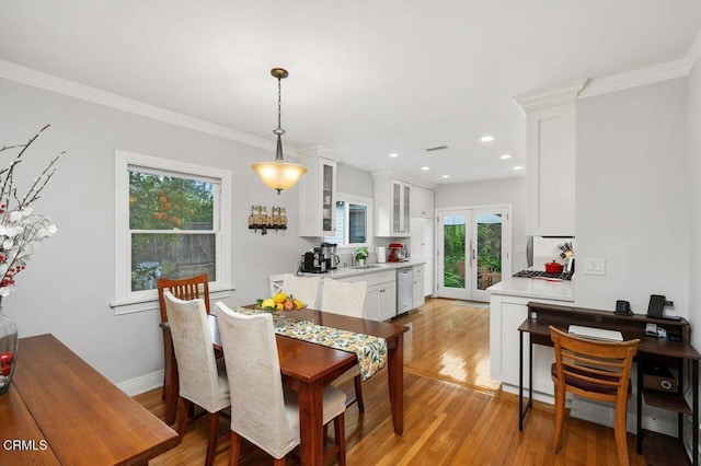 dining area featuring french doors, ornamental molding, sink, and light hardwood / wood-style flooring