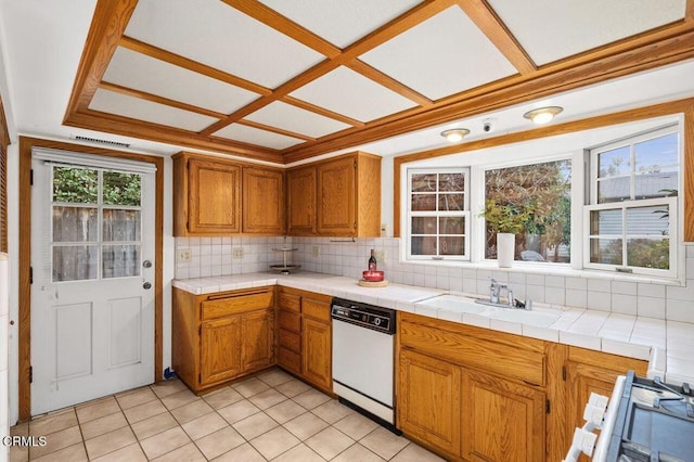 kitchen with tasteful backsplash, tile counters, dishwasher, and sink