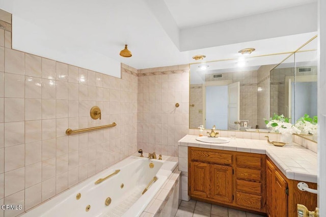 bathroom with tile walls, vanity, tile patterned floors, and tiled bath