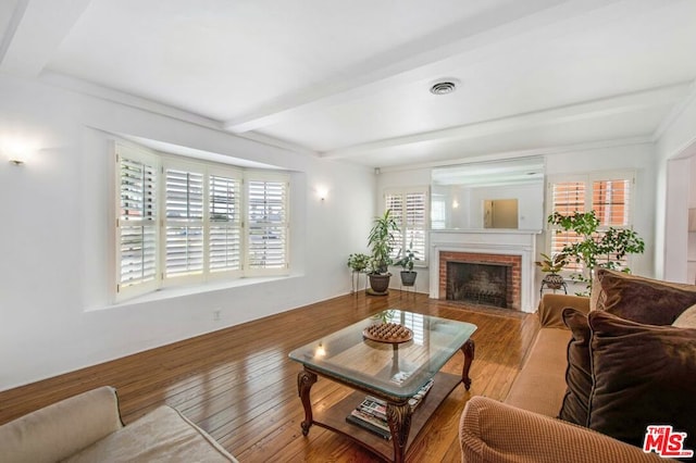 living room featuring hardwood / wood-style flooring, a fireplace, and beamed ceiling