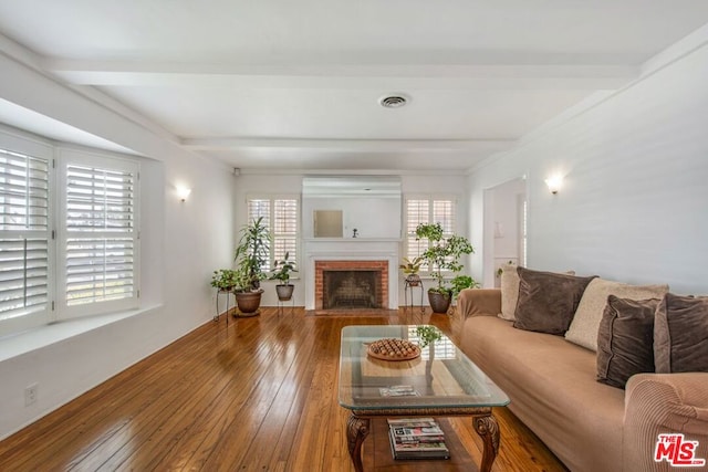 living room featuring a brick fireplace, wood-type flooring, and beamed ceiling