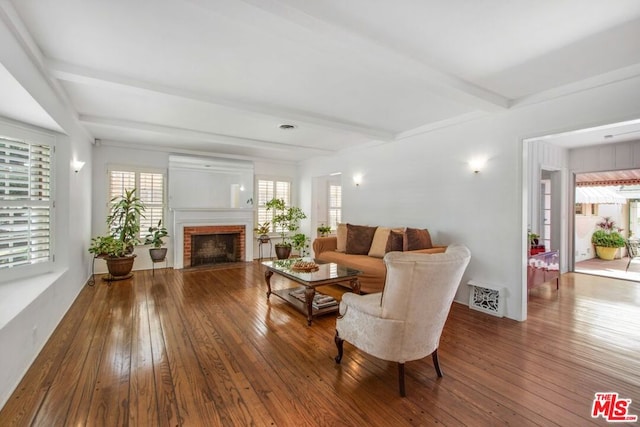 living room featuring hardwood / wood-style flooring, a brick fireplace, and beam ceiling