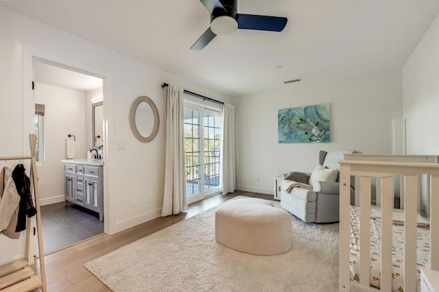 bedroom featuring ensuite bath, wood finished floors, visible vents, and baseboards