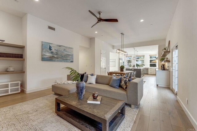 living area featuring a ceiling fan, baseboards, recessed lighting, and light wood-style flooring