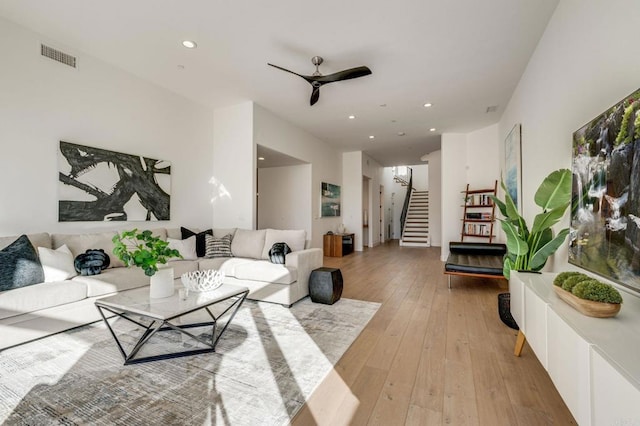 living room featuring stairs, ceiling fan, light wood finished floors, visible vents, and recessed lighting