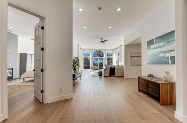 hallway featuring baseboards, recessed lighting, and light wood-style floors