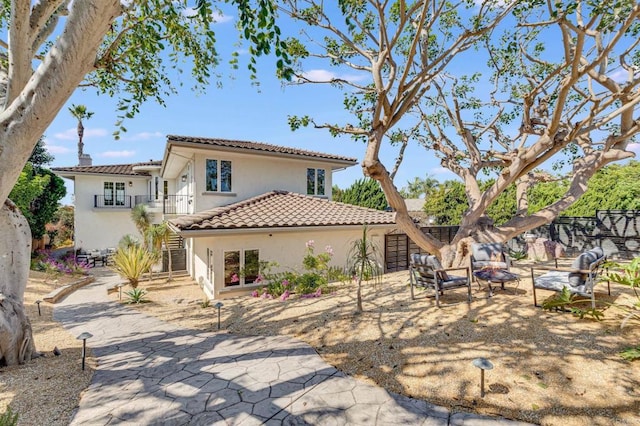 rear view of property with a tile roof, stairs, an outdoor fire pit, a patio, and stucco siding