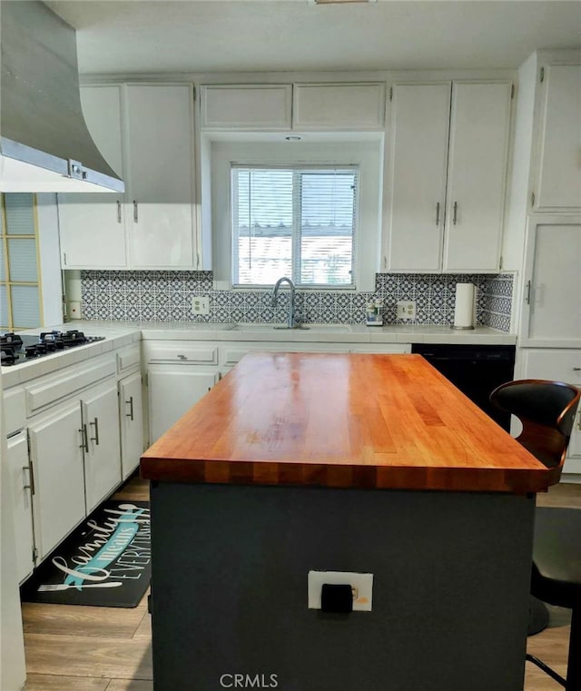 kitchen with white cabinetry, range hood, and a kitchen island