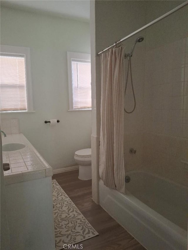 full bathroom featuring wood-type flooring, shower / bath combo, vanity, and toilet