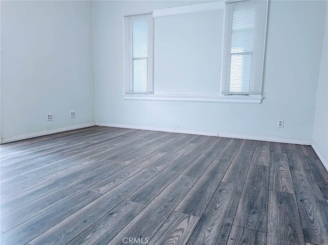 empty room with dark wood-type flooring and plenty of natural light