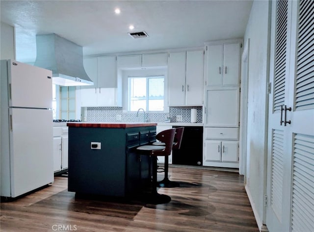 kitchen featuring white refrigerator, white cabinets, and backsplash